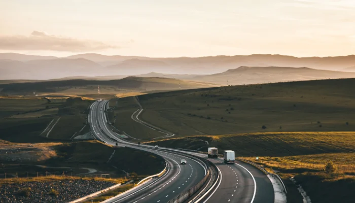 Comparativo regras ANTT anteriores x novas regras ANTT  representado por uma estrada com alguns caminhões.