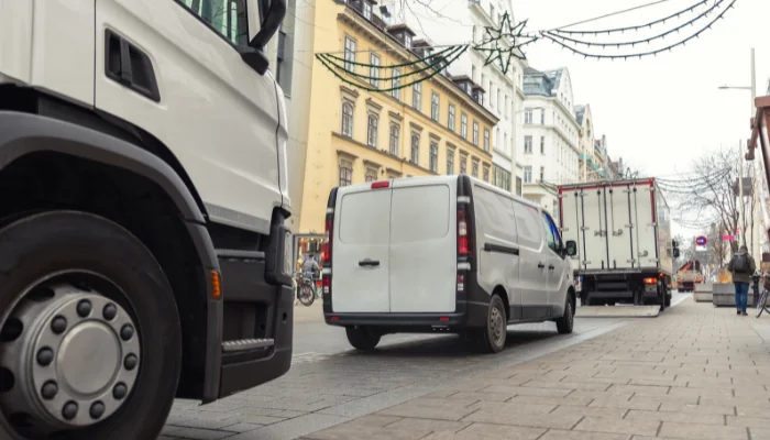 Seguro para Carga Fracionada representado por caminhão e van em trânsito na rua.